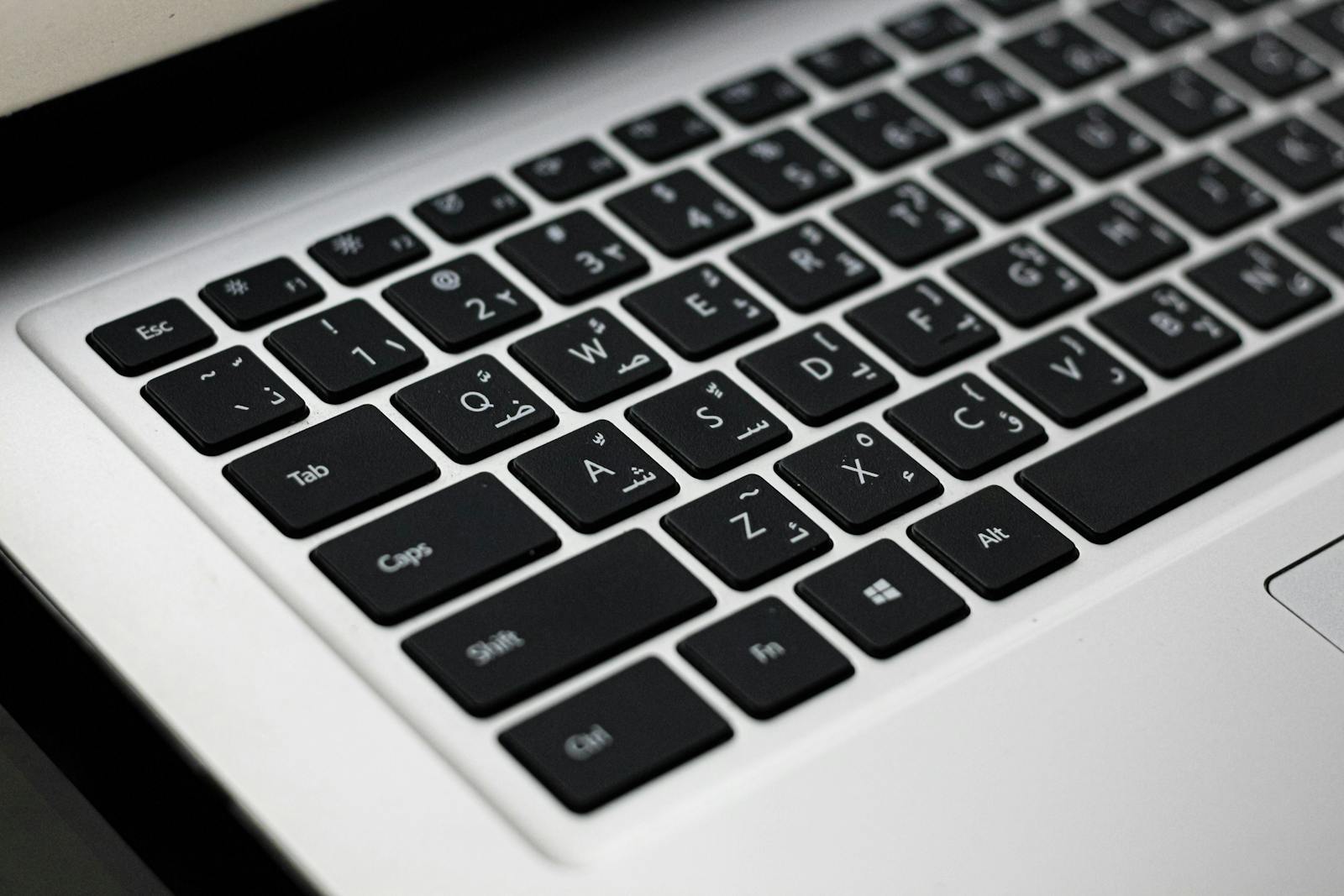 Primer plano del teclado oscuro de una computadora portátil con todas las teclas alfanuméricas visibles